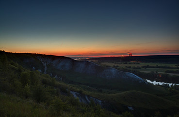 Stars of outer space in the night sky over the river valley. Landscape in the twilight on long exposure.