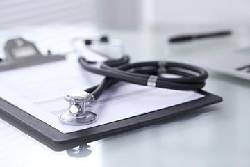 Stethoscope lying at the desk with medical history records and laptop computer. Medicine doctor's working table concept