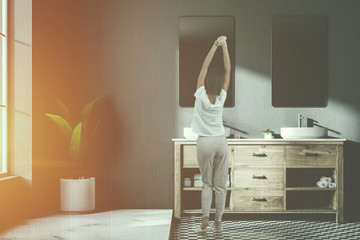Woman near a twin sink in a gray bathroom