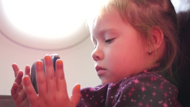 Kid girl passenger watch slide type smart phone display in a plane during flight