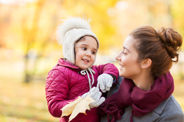 family, season and people concept - happy mother and little daughter with autumn maple leaves