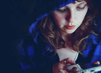 Chica joven usando su teléfono móvil durante la noche 