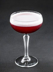 Cold red fruit cocktail in tall glass over dark background. Summer drinks and alcoholic cocktails.