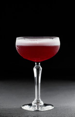 Cold red fruit cocktail in tall glass over dark background. Summer drinks and alcoholic cocktails.