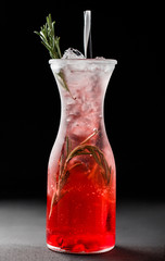 Fresh red strawberry lemonade with rosemary and ice in glass jar over dark background. Summer drinks and cocktails.