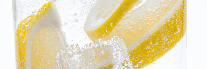Slices of fresh juicy lemon drop into the cocktail with crystal clear water.