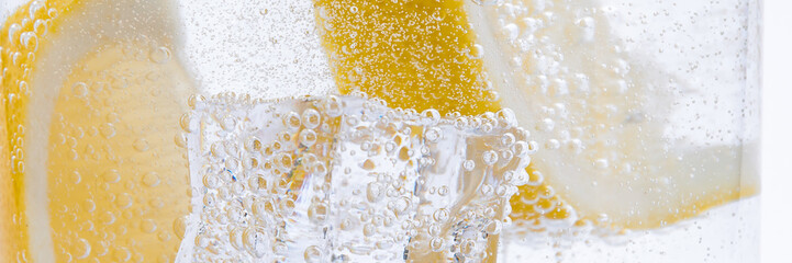 Slices of fresh juicy yellow lemon with ice in clear water. - obrazy, fototapety, plakaty