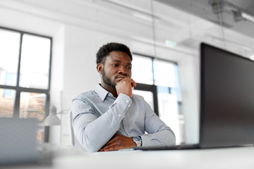 business, people and technology concept - african american businessman with laptop computer working at office