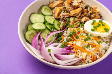 Hawaiian Pake salad with mussels, boiled egg, red onion, cucumber and rice, with black sesame. in a gray plate. On a purple colored trendy background in 2018. copy space, top view