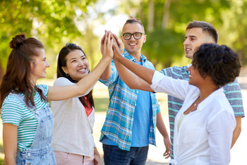 success, friendship and international concept - group of happy smiling friends making high five in park