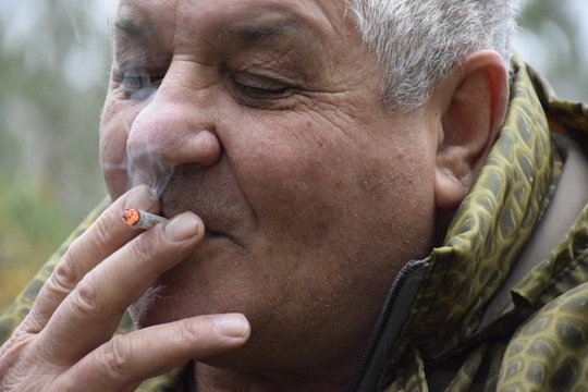 бедный кавказский старик курящий окурок  