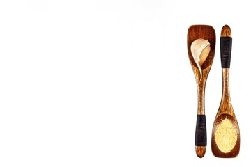 Garlic clove and garlic powder on a wooden spoon, isolated on white. Traditional aromatic spices. Medicinal spices.