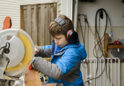 Boy using ear protectors while working at backyard