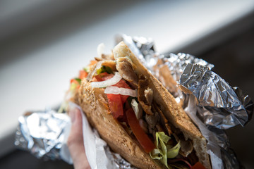 Mann isst Döner im Fladenbrot mit Salat und Kalb Fleisch in Aluminiumfolie 