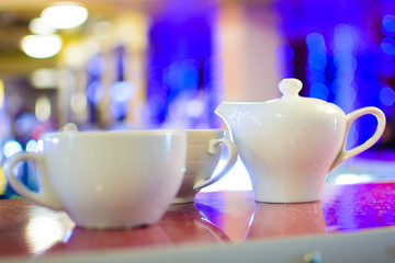 kettle and two cups for tea on the table on a background of blurry bokeh