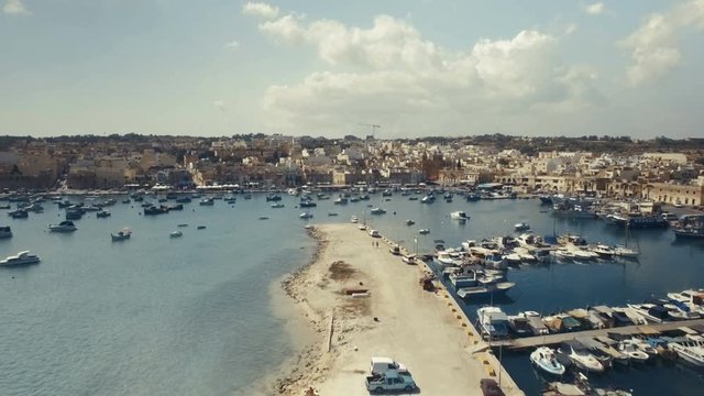 Scenic Aerial shot in Marsaxlokk flying towards a small church