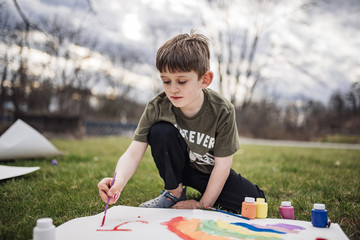 Boy painting on paper at park