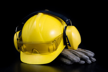 Helmet and workwear on a black working table. Accessories for construction workers.