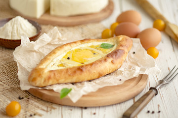 KHACHAPURI or hachapuri filled pie with egg and cheese. Open pie with egg and cheese Flatbread with egg and cheese.