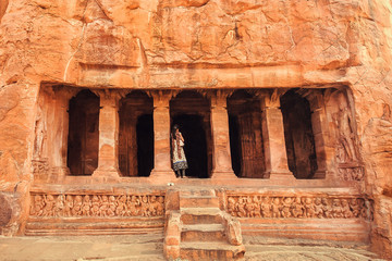 Indian woman standing on stairs to 6th century cave Hindu temple. Old architecture landmark in Badami, India