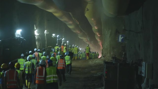 Construction workers walking into a large tunnel
