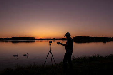 Silhouette von einem Fotografen und Schwan beim Sonnenuntergang am Rhein  Iffezheim