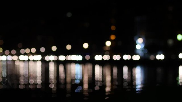 Night traffic in Thessaloniki Greece - running car lights reflected in Aegean Sea water
