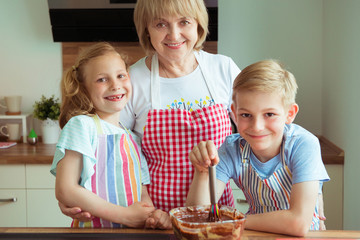 Portrait of happy beautiful grandmother and her grandchildren in modern kitchen