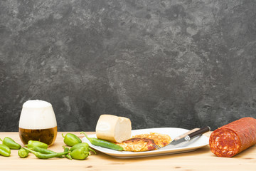 Tortilla con chorizo y pimientos picantes, un vaso de cerveza con espuma