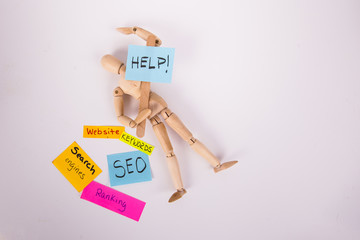 Help sign held by wooden jointed manikin doll laying on solid white background assorted colored...