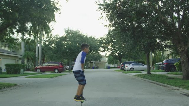 Slow motion of a kid jumping on a pogo stick in a rural neighborhood