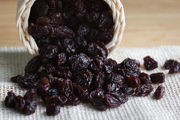 Pile of Dried raisin on sackcloth on wooden desk.