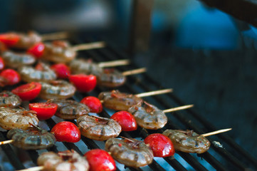  Marinated hot prawns with grilled tomatoes closeup. Seafood on the grill. protein health food. Select focus.