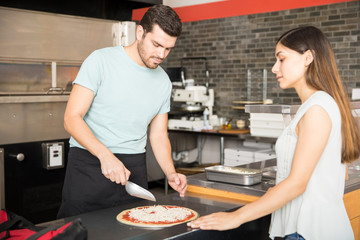 Cook in the kitchen putting the ingredients on the pizza