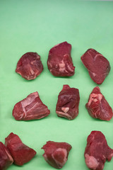 Raw beef tips on green background