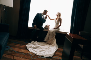 Wedding photo shooting.Married couple embracing and looking at each other.Holding bouquet.Sensual...