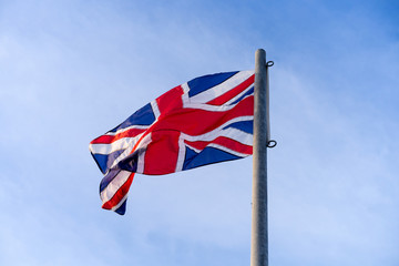 Waving or Flying United Kingdom's Flag caled Union Jack on steel pool with blue sky at back