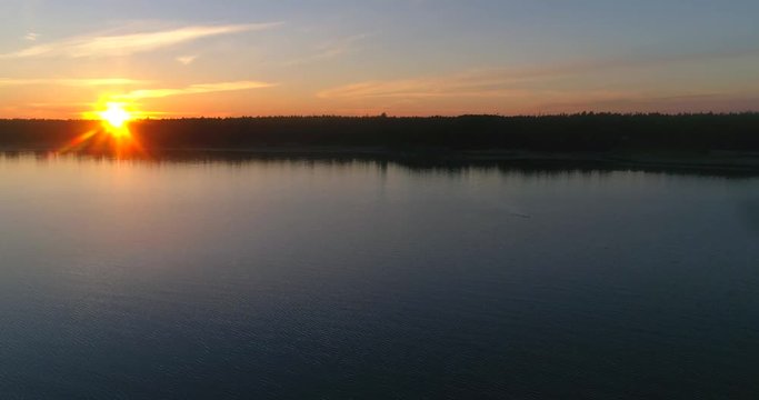 Sunset at a calm sea, C4K aerial view towards a calm, clear and low waters of the gulf of finland, on a sunny summer evening dusk, in Hanko, Finland