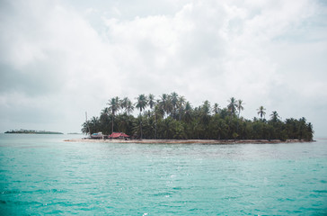 Tropical paradise island with small hut in the middle of the turquoise blue Caribbean Sea in the San Blas Islands, off the coast of Panama
