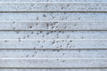 background of metal holey fence with holes from gun shots