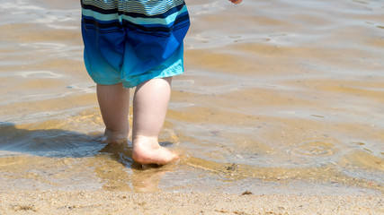 Toddler boy playing in a big lake on a summer day