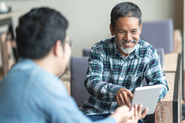Happy old short beard asian man sitting, smiling and listen to partner that showing presentation on...