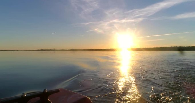 Sunset at Calm sea, C4K view of calm, clear and reflecting waters of the gulf of finland, from a boat, on a sunny summer evening sunset, in Hanko, Finland