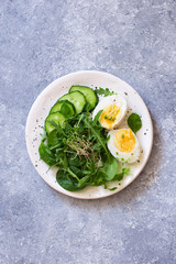 Fresh salad and boiled eggs on grey stone background