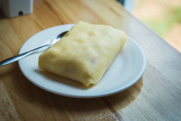 Crepe in a white dish placed on a table in a coffee shop.