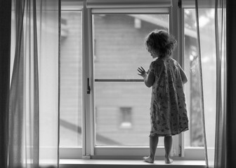 girl in pajamas on the windowsill in black and white with the light from the window