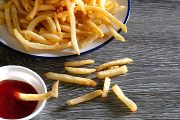 French fries and raw potato on wooden table in dim light