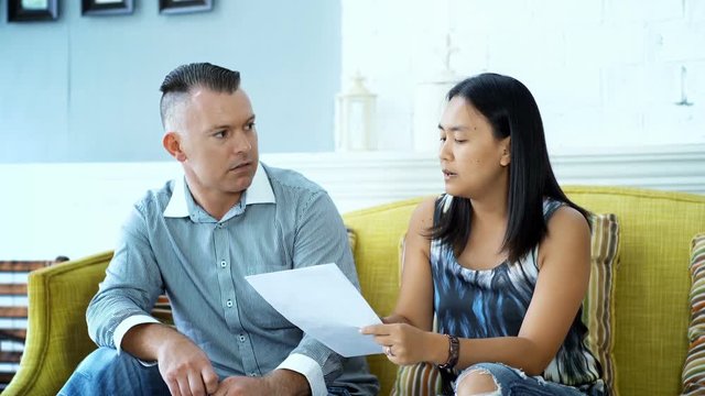 Young couple arguing while reading document in the living room