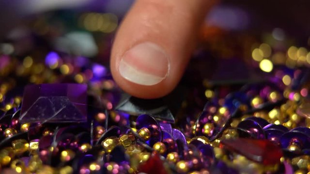 Extreme closeup of hot glue going onto a purple costume and a finger pressing a rhinestone into place.