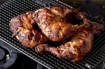 A stack of grilled tandoori spiced chicken legs on a wire rack.